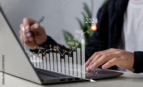 Businessman working on digital laptop computer with digital graph chart graphic, positive indicators in 2024, business calculate financial data, Digital marketing, finance, trade stock market concept.