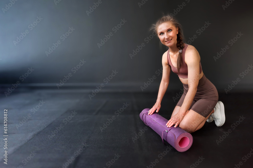 Fitness background for your business. The girl is engaged in pilates on a pink yoga mat. Class Stretching in the gym on a black rubber covering. Exercise stretching cobra. Top view advertising banner. Fitness background for your business. The girl is engaged in pilates on a pink yoga mat. Class Stretching in the gym on a black rubber covering. Exercise stretching cobra. Top view advertising banner.