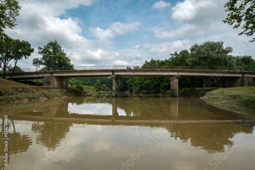 Ponte sobre o rio num dia nublado com o reflexo da ponte sobre a água