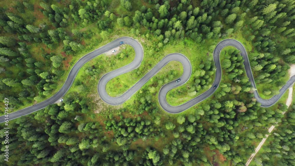 Aerial view of cars wind along the Snake Road, enveloped by the enchanting forests of Giau Pass. Aerial view of cars wind along the Snake Road, enveloped by the enchanting forests of Giau Pass.