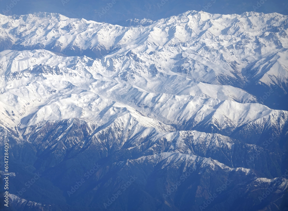 Fototapeta premium View of the high snow-capped peaks of the Main Caucasian Range from the window of a flying aircraft