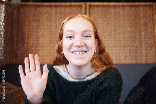 Portrait of smiling woman looking and waiving at camera photo