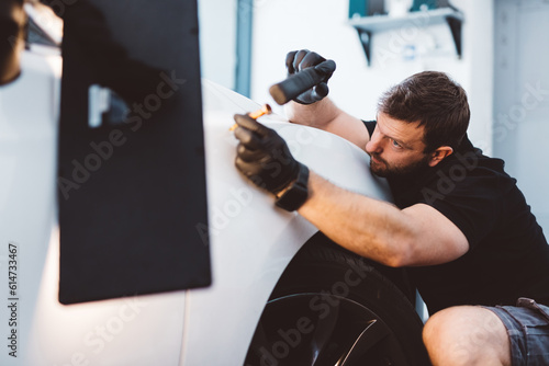 Foto Car mechanic working to remove dent in workshop.