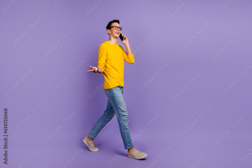 Full size profile side photo of young cheerful smiling man go walk talking on phone isolated on vivid background