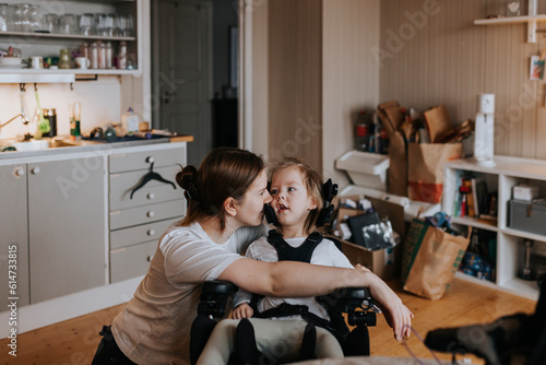 Mother taking care of disabled child in wheelchair at home photo