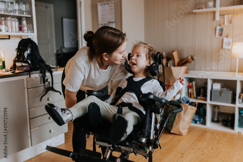 Mother taking care of disabled child in wheelchair at home photo