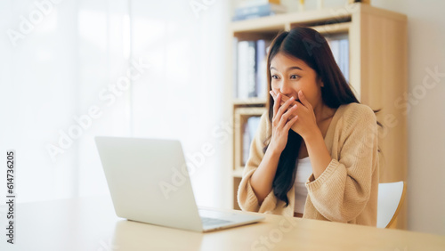 Funny euphoric young asian woman celebrating winning or getting ecommerce shopping offer on computer laptop. Excited happy girl winner looking at notebook celebrating success
