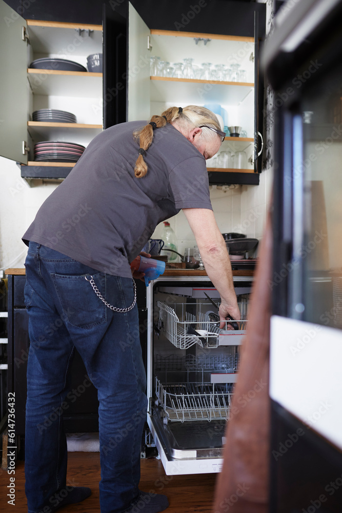 Man in kitchen taking dishes out of dishwasher Man in kitchen taking dishes out of dishwasher