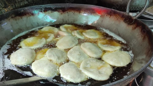 Rajasthani kachori made of daal, onion and refined wheat flour is getting fried in hot oil in a big tawa at halwai farsan shop on the street on india, tasty kachori getting ready. traditional food photo