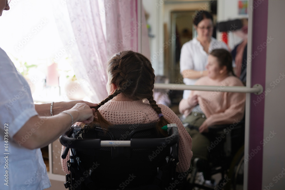 Mother brushing disabled daughter's hair in bedroom Mother brushing disabled daughter's hair in bedroom