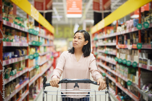 Woman looking at prices during inflation while doing shopping in supermarket photo