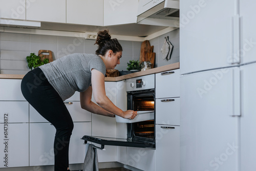Pregnant woman putting dish in oven