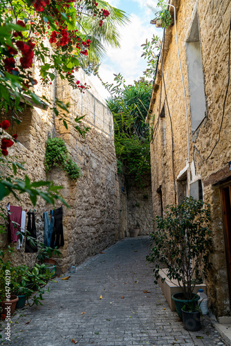 Fototapeta Naklejka Na Ścianę i Meble -  A narrow street by traditional Kyrenia stone houses in the old town. Old city street view in Kyrenia or Girne, Northern Cyprus.