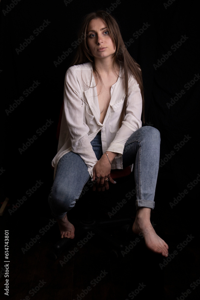 Beautiful young girl in a white shirt and jeans on a black background Beautiful young girl in a white shirt and jeans on a black background