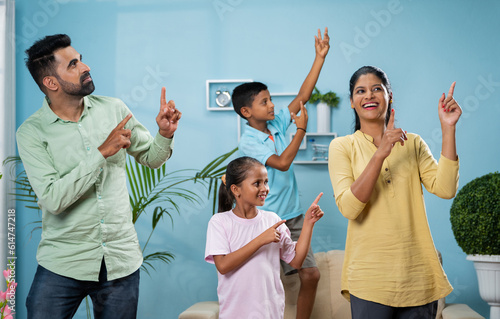Cheerful Indian couple dancing with siblings kids at new home or apartment - concept of leisure activities, carefree living and holidays or vacation.