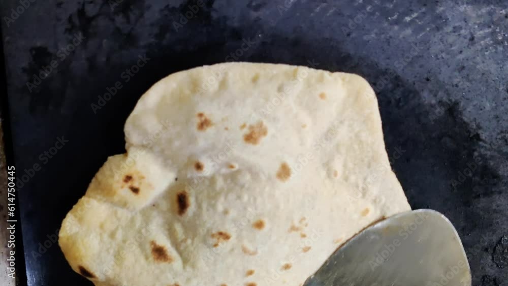 A closeup of an Indian chef skillfully preparing fresh chapatis on a