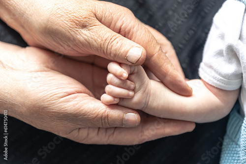 Grandmother holds the hand of the baby, close-up.
