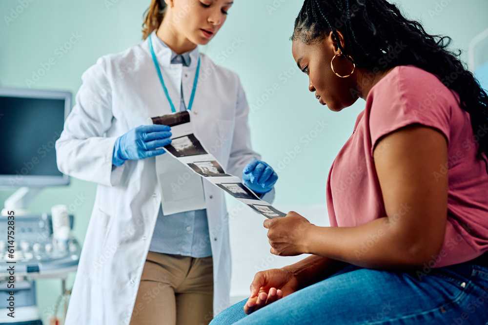 Black woman and her gynecologist analyzing ultrasound images in medical examination room. Black woman and her gynecologist analyzing ultrasound images in medical examination room.