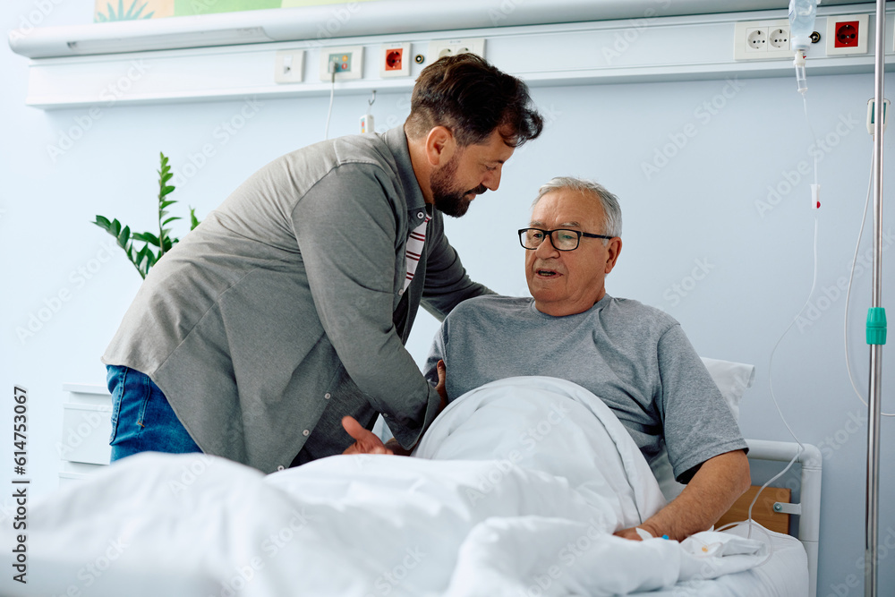 Obraz premium Caring son helps his hospitalized senior father to get up from bed.