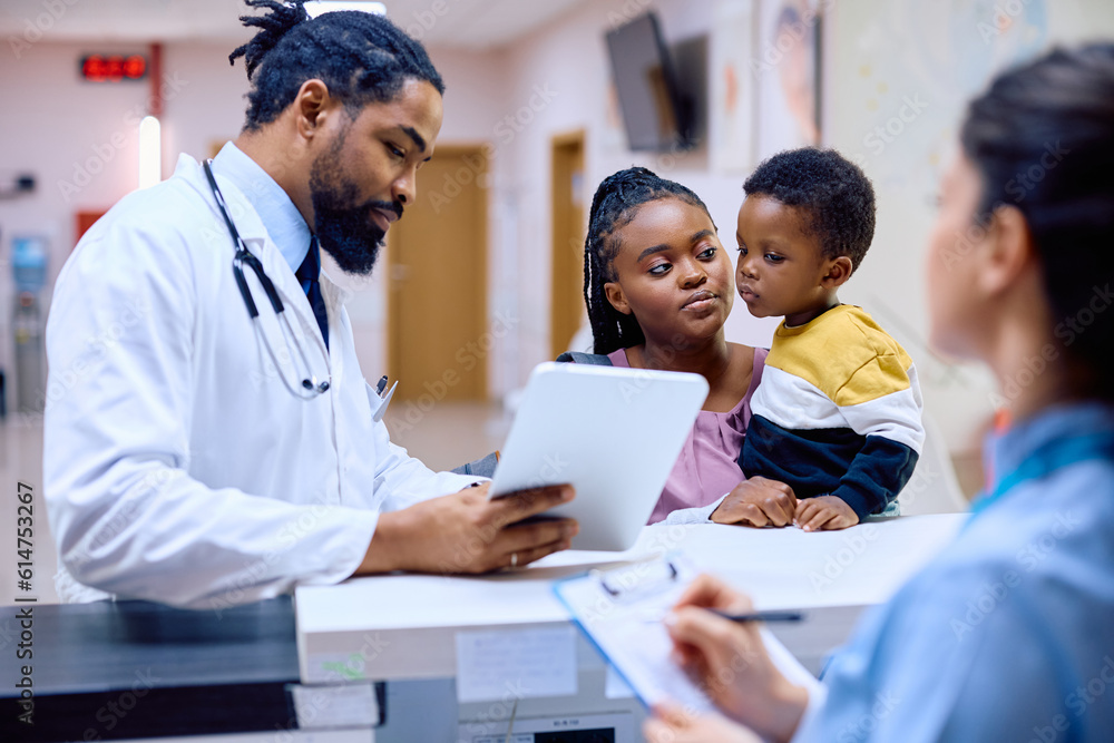 Black mother and son with male pediatrician at reception desk at doctor's office. Black mother and son with male pediatrician at reception desk at doctor's office.