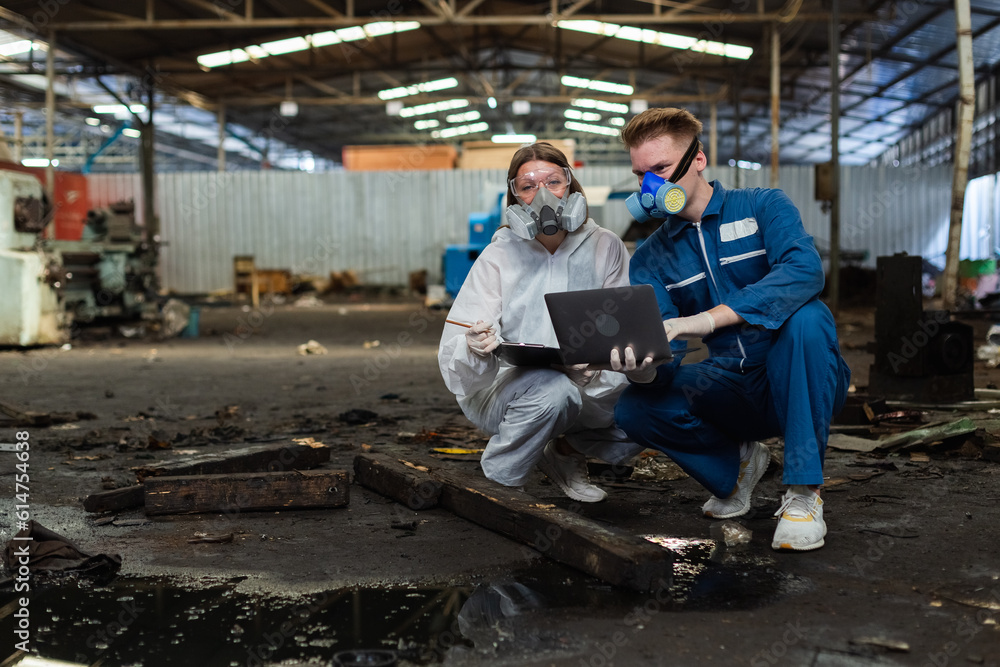 Team inspector chemical and hazmat wearing protective mask using laptop and write note on clipboard. Wastewater chemical residue in factory. Analysing harmful substances to human body environment.