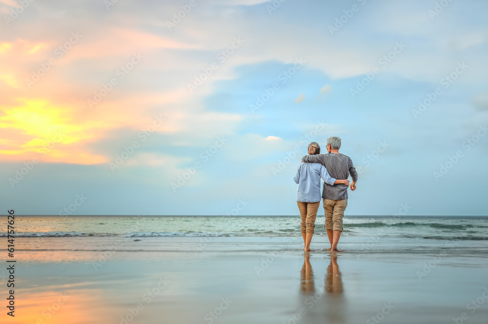 Plan life insurance of happy retirement concepts. Senior couple walking on the beach holding hands at beach sunrise in evening. - obrazy, fototapety, plakaty 