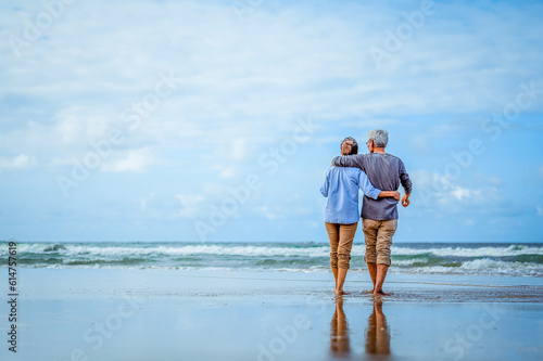 Plan life insurance of happy retirement concepts. Senior couple walking on the beach holding hands at beach sunrise in evening.