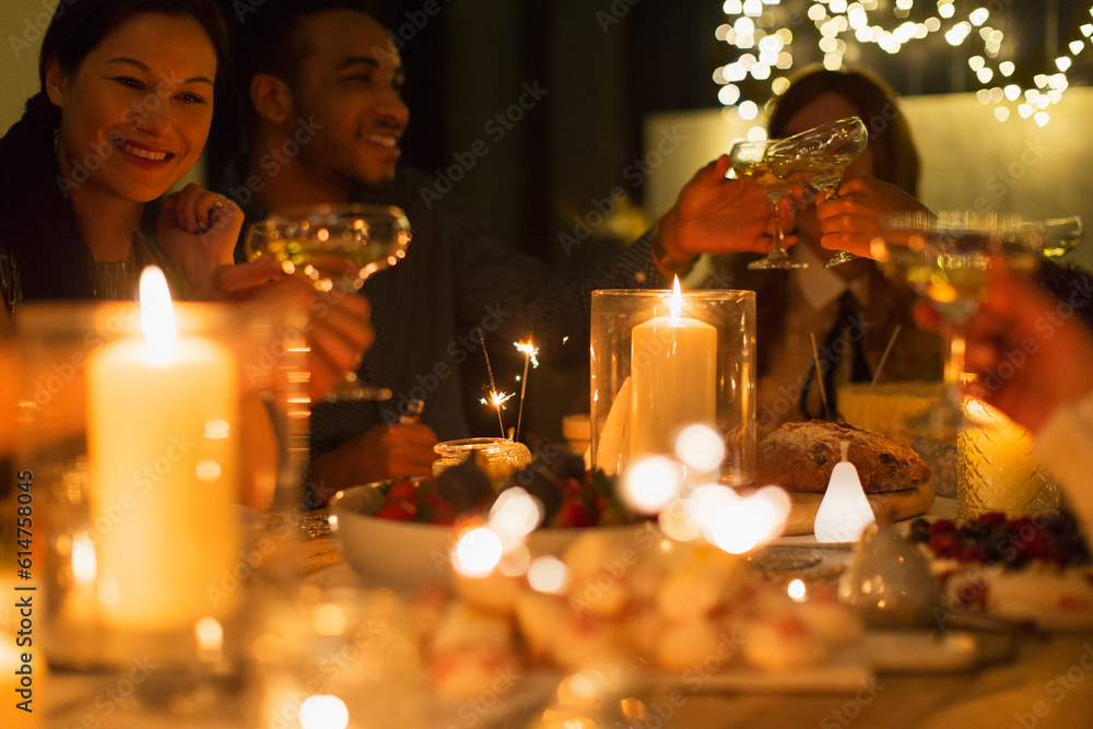 Friends toasting champagne glasses at candlelight Christmas table Friends toasting champagne glasses at candlelight Christmas table