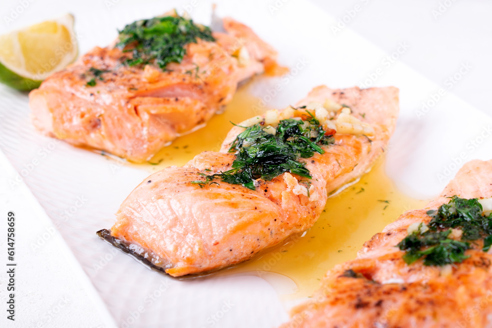 Fried trout steaks served with butter, herbs and garlic on white plate. Hot keto meal Fried trout steaks served with butter, herbs and garlic on white plate. Hot keto meal