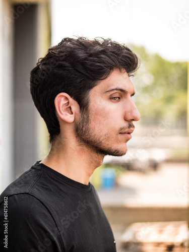 Head and shoulder sideview shot of one handsome young man in urban setting