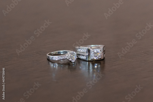 Wedding rings on a dark brown wood grain background. A couple's diamond ring against a wooden background.