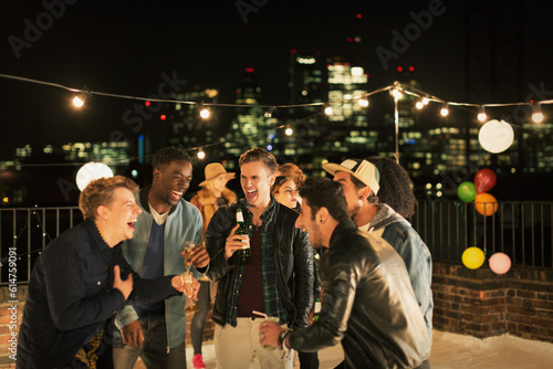Photography Young men drinking and laughing at rooftop party