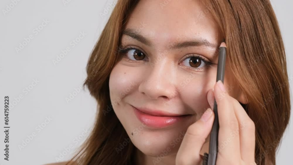 Young beautiful woman applying makeup her eyebrows for strong growth. looking at camera Young beautiful woman applying makeup her eyebrows for strong growth. looking at camera