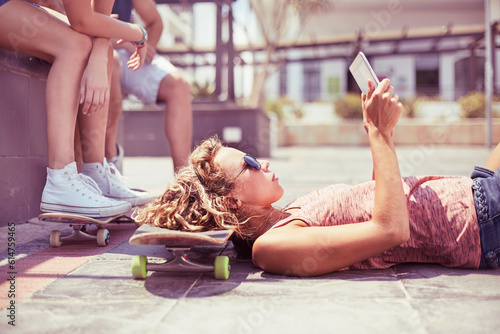 Young woman with digital tablet laying on skateboard