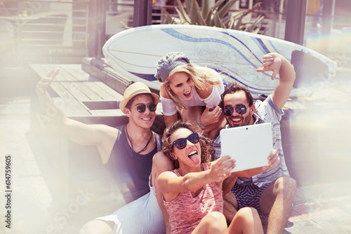 Playful young friends taking selfie in front of surfboard digital tablet