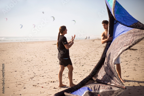 Obraz na płótnie Woman instructing man with kiteboarding kite on sunny beach