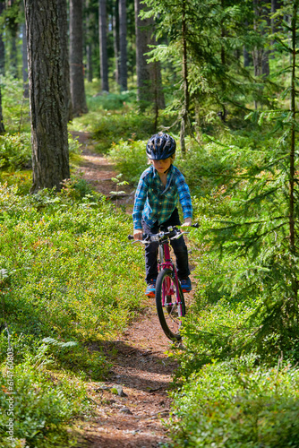 Boy riding bicycle on trail in woods