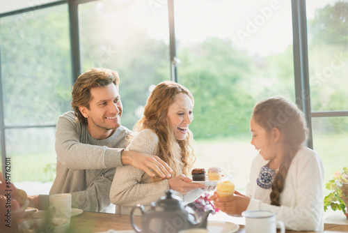 Playful family eating cupcakes at table