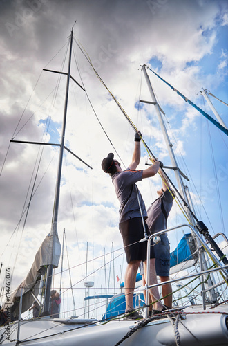 Men adjusting sailing equipment on sailboat