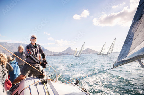 Man adjusting sailboat rigging on sunny ocean
