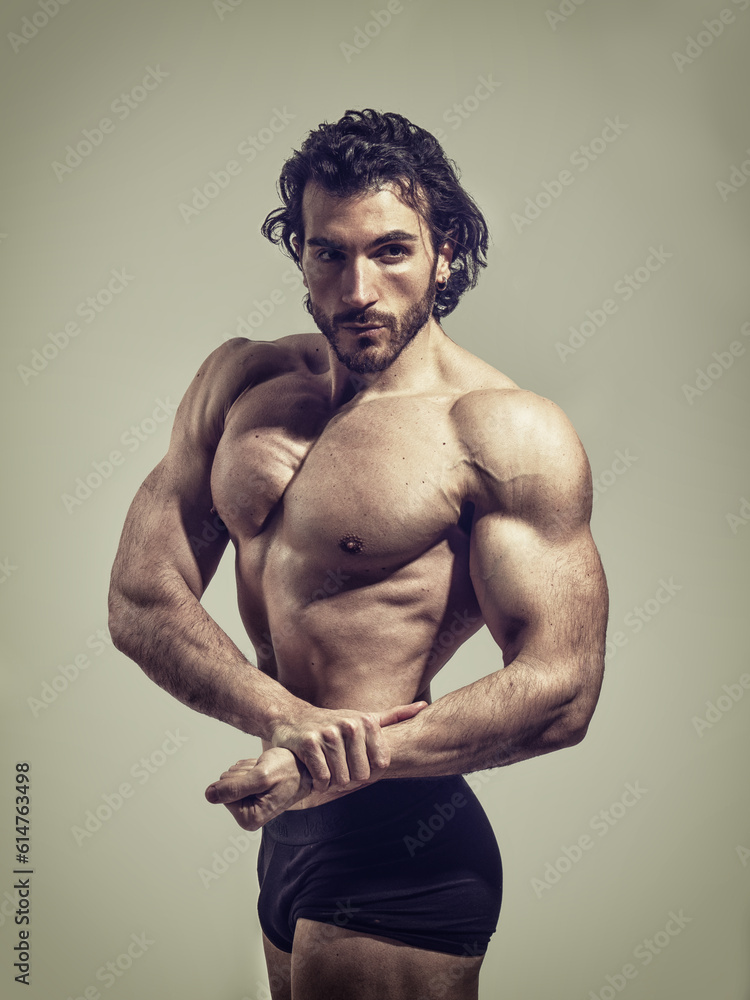 Fototapeta premium Handsome bodybuilder doing classic bodybuilding pose in studio