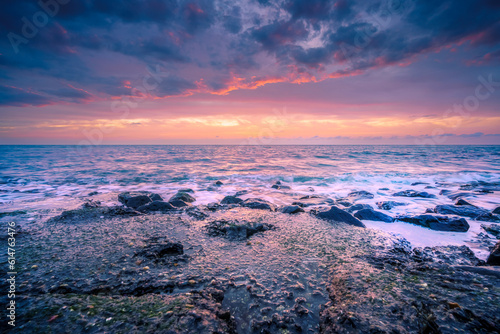 Breathtaking sunset with pastel colors and smooth white water along rocky dutch coast