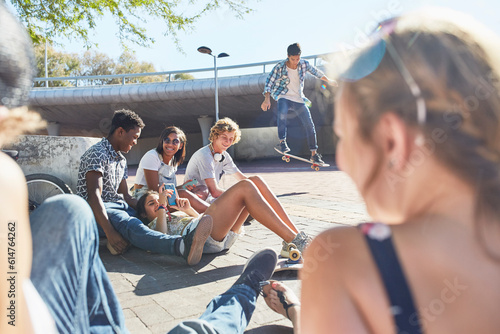 Canvas Print Teenage friends hanging out skateboarding at sunny skate park