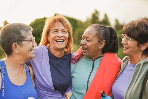 Happy multiracial women having fun together hugging each other at park after sport workout