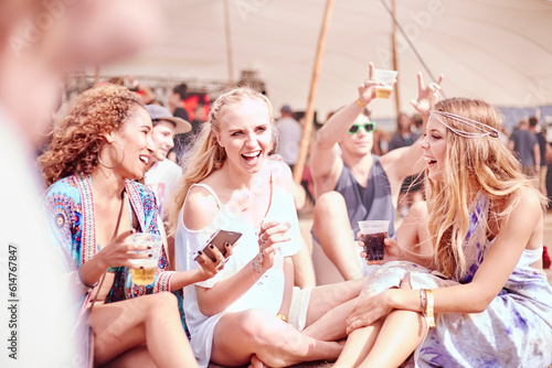 Young women hanging out drinking at sunny music festival © KOTO