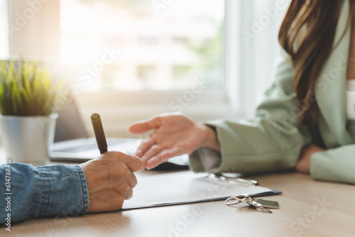 Real estate agent or realtor landlord advice buyer client to sign mortgage document. close-up focus on hand of tenant holding pen signing paperwork. photo