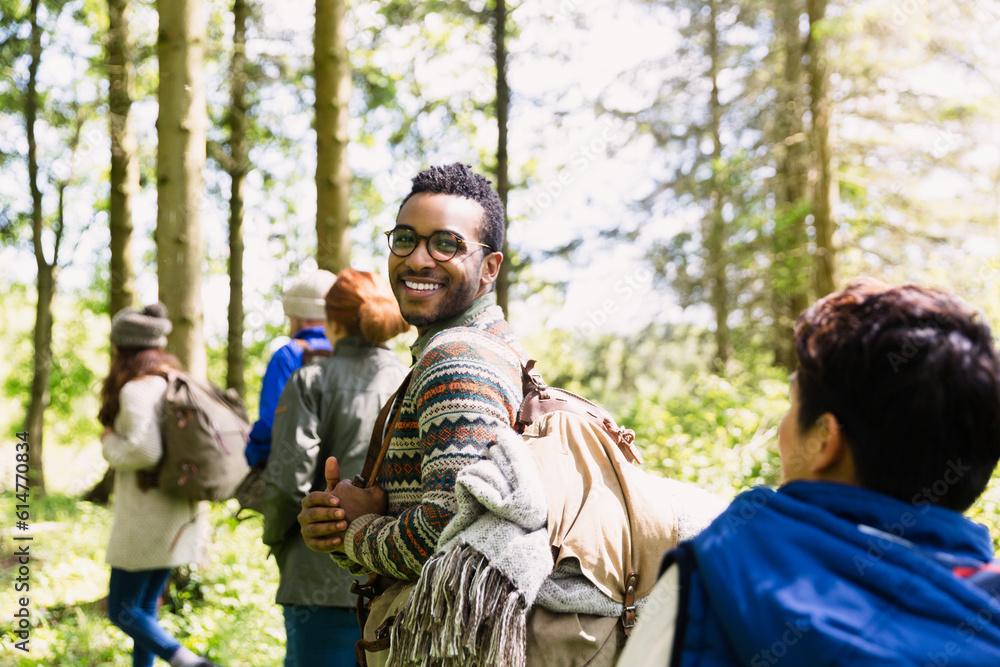 Portrait smiling man with backpack hiking in sunny woods Portrait smiling man with backpack hiking in sunny woods