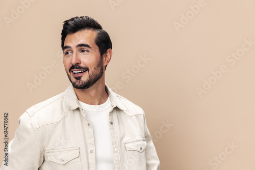 Portrait of a stylish man smile closeup on a beige background in a white t-shirt, fashionable clothing style, copy space © SHOTPRIME STUDIO