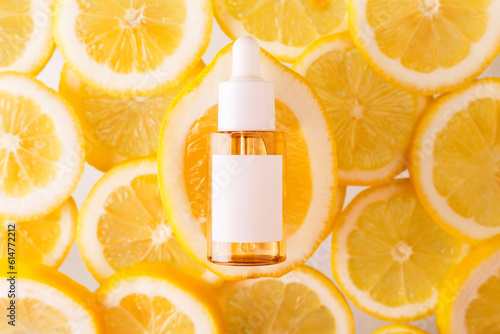 Vitamin C formula ampoule. Serum in transparent bottle with lemon flat lay on skice of lemons bright yellow background. Beauty and health concept. Mockup for your design with copy space.. photo