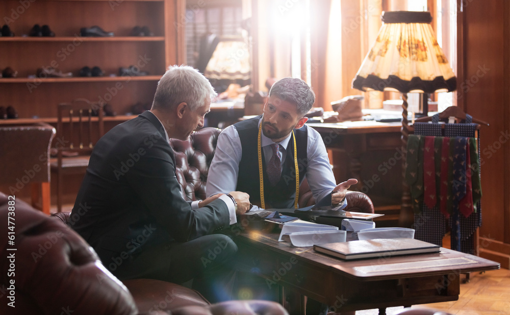 Tailor and businessman talking in menswear shop Tailor and businessman talking in menswear shop